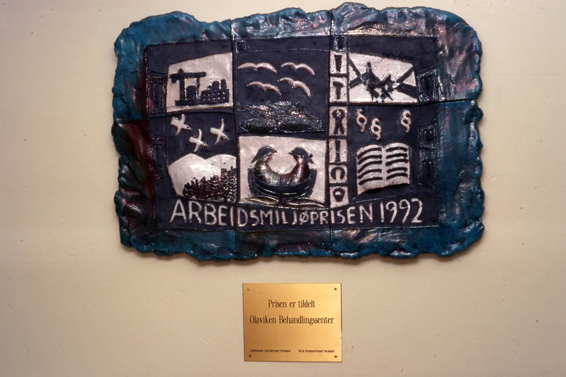 Et bilde i stein med måker, båter og folk