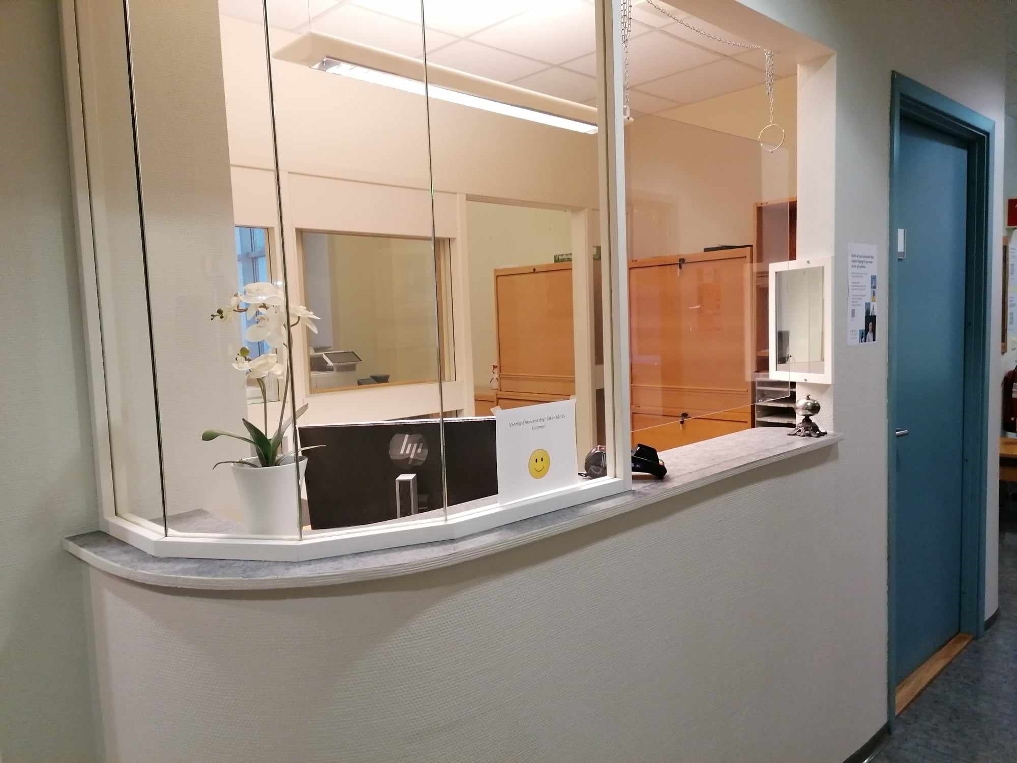 En resepsjon med en glassvegg og en hvit disk med en plante