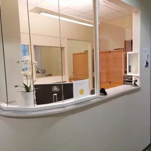 En resepsjon med en glassvegg og en hvit disk med en plante