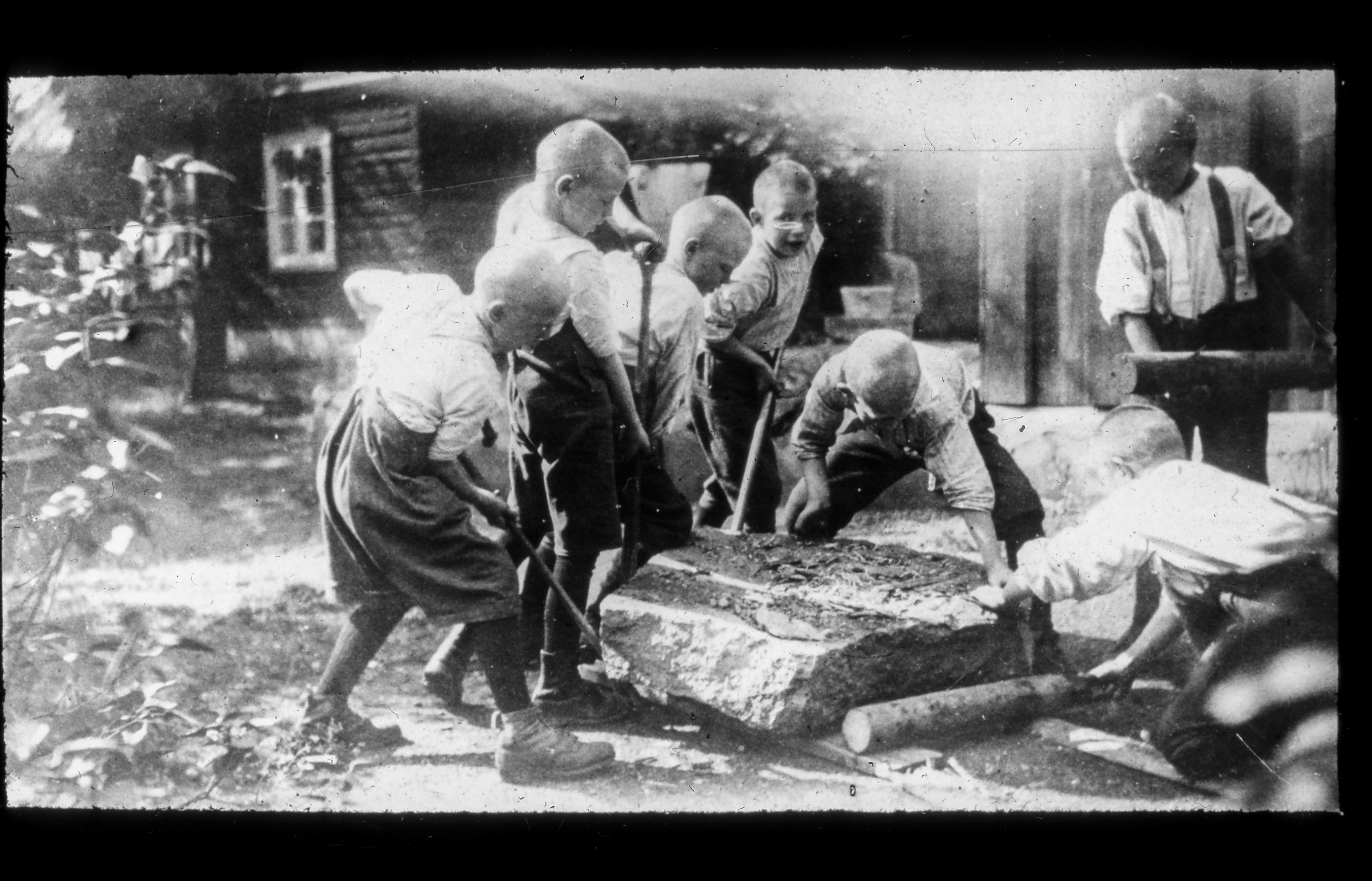 Gutter som  som jobber med å flytte en stein