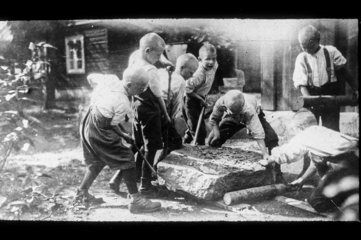 Gutter som  som jobber med å flytte en stein