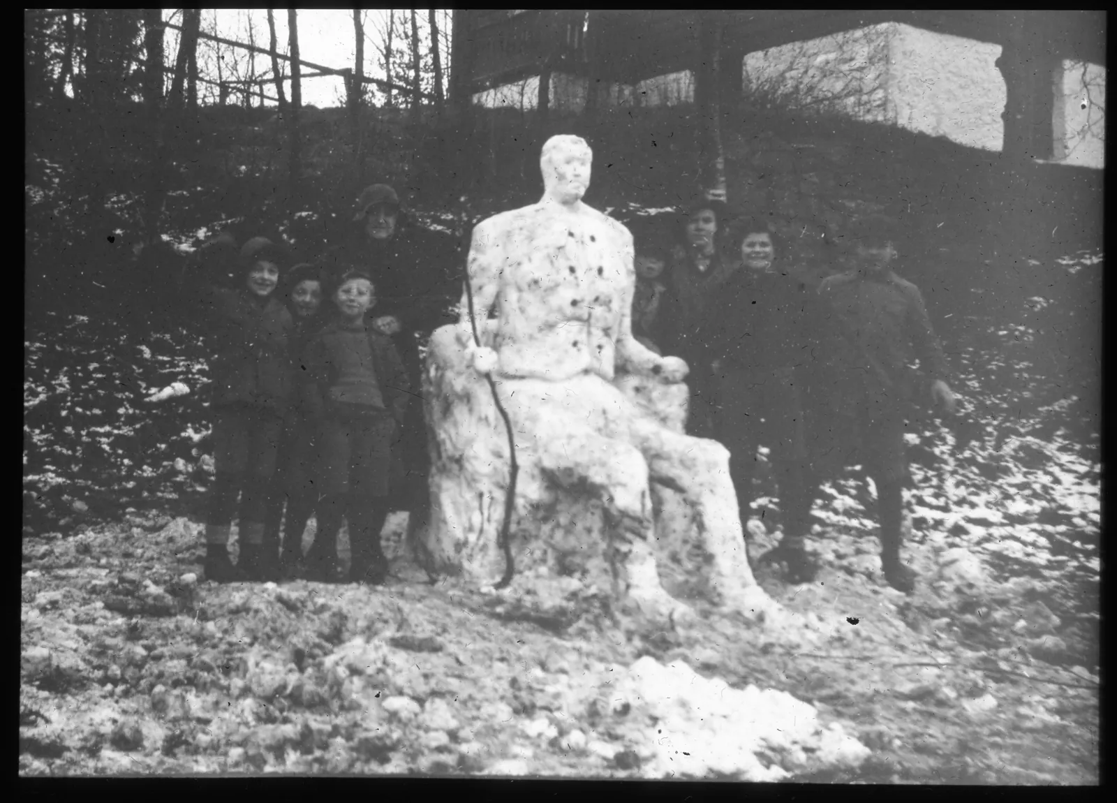 Gutter som har bygget en stor snømann som sitter i en stol