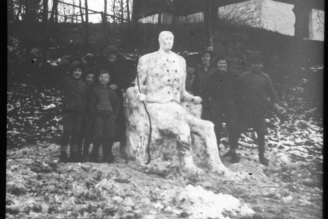 Gutter som har bygget en stor snømann som sitter i en stol